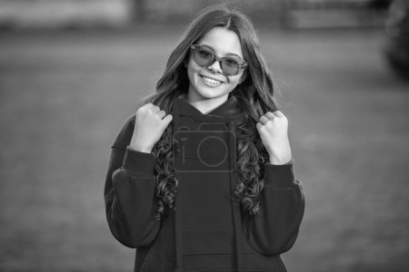 fashion teen girl smile and wear glasses. photo of fashion teen girl wear hoodie. fashion teen girl outdoor. fashion teen girl outside.