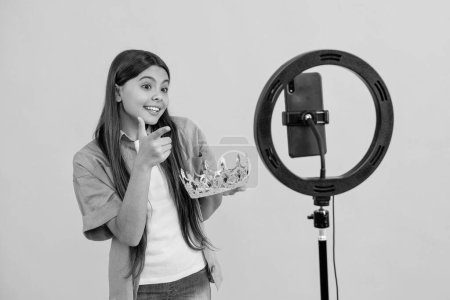 teen girl influencer with crown, pointing finger. teen girl influencer with crown isolated on yellow. teen girl influencer with crown in studio. teen girl influencer with crown on background.