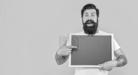 bearded man offer advertisement isolated on yellow, banner. man offer advertisement on background with copy space. man offer advertisement in studio. photo of man offer advertisement at blackboard.