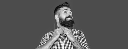 pleased bearded man wear checkered shirt on grey background.