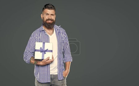Téléchargez les photos : Mature barbu gars avec boîte cadeau sur fond gris. Journée des hommes. - en image libre de droit