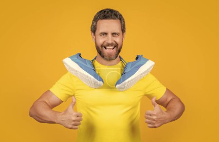 positive fitness man with sportswear isolated on yellow. fitness man with sportswear on background. fitness man with sportswear in studio. photo of fitness man with sportswear shoes.