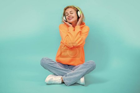 photo of cheerful woman has music lifestyle wear headphones. woman has music lifestyle isolated on blue. woman has music lifestyle in studio. woman has music lifestyle on background.