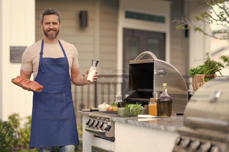 barbecue man with salmon in apron, advertisement. photo of barbecue man with salmon fish. barbecue man with salmon. barbecue man with salmon outdoor.