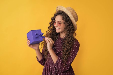 Téléchargez les photos : Kid smile with curly hair hold present box on yellow background. - en image libre de droit