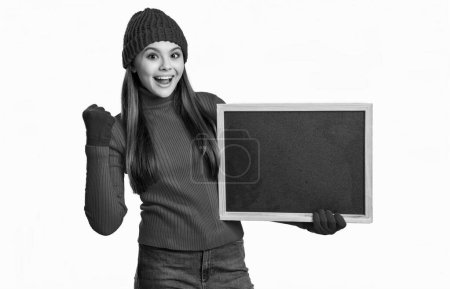 surprised teen girl with school blackboard. teen girl hold school blackboard isolated on white background. teen girl holding school blackboard in studio. photo of teen girl having school blackboard.