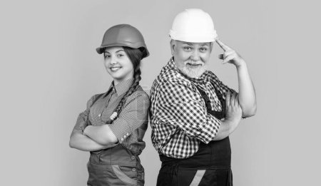smiling kid and grandfather builder in helmet on yellow background.