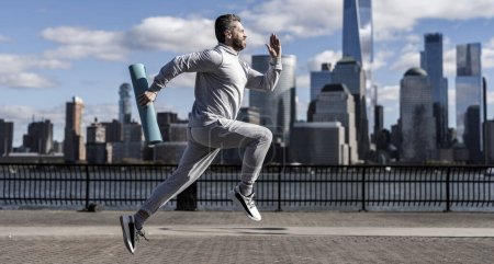 The sportsman running at view to New York. Man sportsman running for exercise in active wear. Sportsman jogger running. Sport runner in Manhattan. Breaking records.