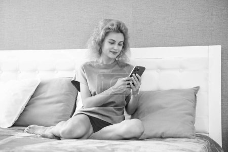 smiling girl relax at home and texting on phone. girl texting on phone on the bed. phone texting of girl.