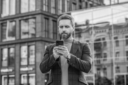 Photo for Photo of man messaging on smartphone in jacket. man messaging on smartphone outdoor. man messaging on smartphone in the street. man messaging on smartphone outside. - Royalty Free Image