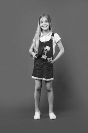 joyeux adolescent fille skateboarder sur fond. photo de jeune fille skateboarder. adolescent fille skateboarder isolé sur violet. adolescent fille skateboarder dans studio.