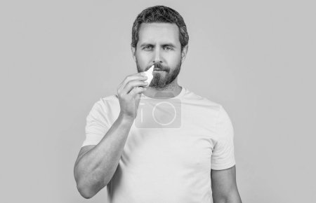 Photo for Man use nasal medicine in studio. photo of man with nasal medicine drops. man with nasal medicine isolated on yellow. man with nasal medicine on background. - Royalty Free Image