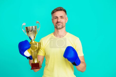 Man sportsman boxer hold champion cup as winner in boxing sport isolated on blue.