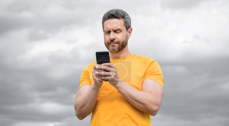 man chatting on smartphone on sky background.