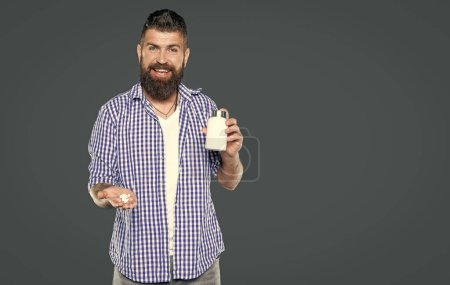 mature man smile hold medication pill on grey background.