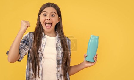 surprised teen girl with shampoo cosmetics in studio. teen girl with shampoo cosmetics on background. photo of teen girl with shampoo cosmetics. teen girl with shampoo cosmetics isolated on yellow.