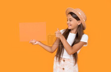 happy teen girl with copy space on orange paper on yellow background. thumb up.