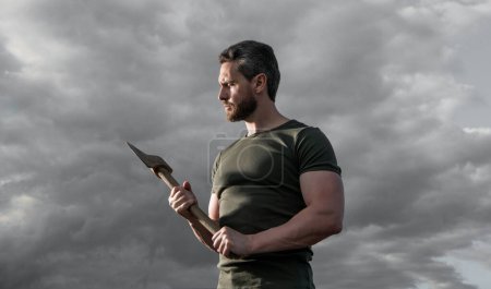 man with axe. caucasian man hold ax. brutal man on dramatic sky background.