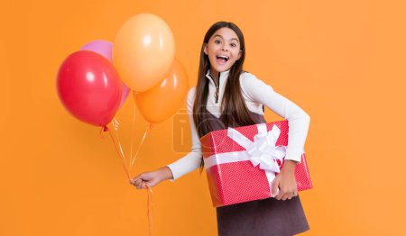 Téléchargez les photos : Amazed child smile with party colorful balloons and present box on yellow background. - en image libre de droit