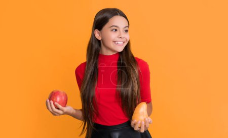 Téléchargez les photos : Heureux enfant tenir pomme et poire sur fond jaune. - en image libre de droit