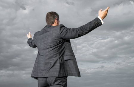 Professional man back view sky background. Man spreading arms wide open. Man in suit outdoors.