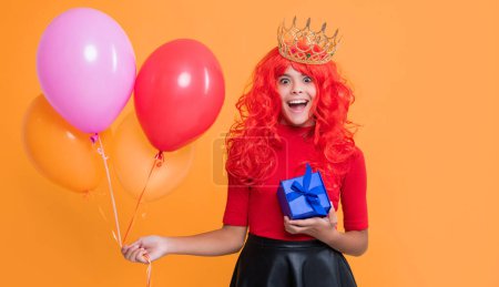 happy child in crown with gift box and party balloon on yellow background. wow.