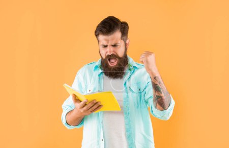 Photo for Shouting hipster guy reading notebook on yellow background, success. - Royalty Free Image