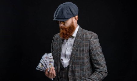 Englishman with money. Rich man in retro suit. Brutal gentleman has successful business. Man with casino money. Bearded man businessman. Rich Englishman. Retro man isolated on black.