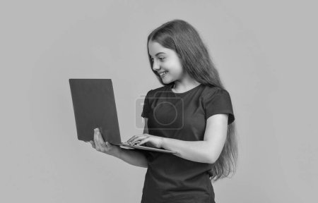 smiling child with laptop on yellow background. online education