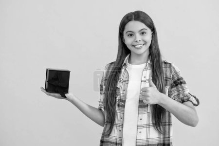 Photo for Teen girl after successful shopping, thumb up. teen girl with shopping box isolated on yellow. teen girl shopping with present in studio. teen girl holding shopping box on background. - Royalty Free Image