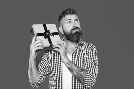 Téléchargez les photos : Homme barbu mature rêveuse avec boîte actuelle sur fond gris. - en image libre de droit