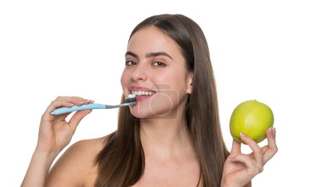 Téléchargez les photos : Femme avec sourire blanc brossant les dents avec brosse à dents électrique tenir pomme. - en image libre de droit
