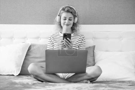 Photo for Smiling woman shopping online on phone. woman has shopping online with phone chat at home. online shopping of woman in headphones. - Royalty Free Image