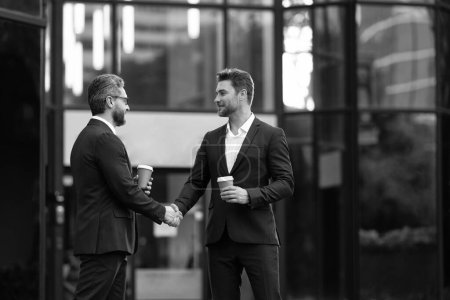 Photo for Two business partners hold coffee dealing negotiation, copy space. photo of two business partners dealing negotiation. two business partners dealing negotiation. two business partners dealing - Royalty Free Image
