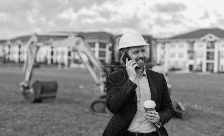 Unternehmer und Bauinvestor lächeln im Freien. Unternehmer Bauinvestor vor Ort. Unternehmer Bauinvestor mit Telefon. Unternehmer Bauinvestor bei Kaffeepause.