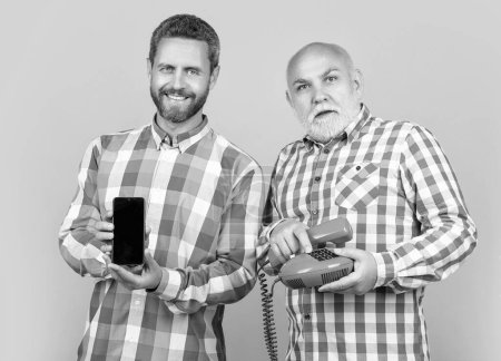 glückliche Männer mit vs Technologie im Studio. Männer mit Technik im Hintergrund. Foto von Männern mit Handy und Telefon. Männer mit Technik isoliert auf gelb.