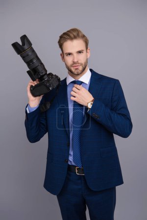 Business photographer with camera. Journalist man taking photo isolated on grey. Paparazzi photographer. Businessman hold photo camera. Press photographer. Photojournalist in business suit.