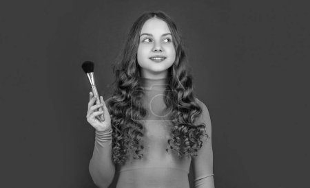 Teenager-Make-up. positive Kind mit lockigem Haar halten Puderpinsel für Make-up.