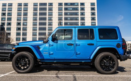 Téléchargez les photos : New York, États-Unis - Mars 31, 2024 : 2024 Jeep Wrangler Unlimited Sahara véhicule à cicatrice sportive bleu stationné à l'extérieur, vue latérale. - en image libre de droit