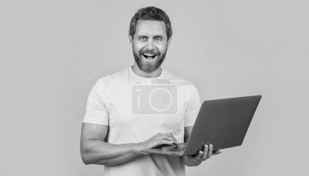 Téléchargez les photos : Homme heureux programmeur en studio. photo de l'homme programmeur avec ordinateur portable. programmeur homme isolé sur jaune. homme programmeur sur fond. - en image libre de droit