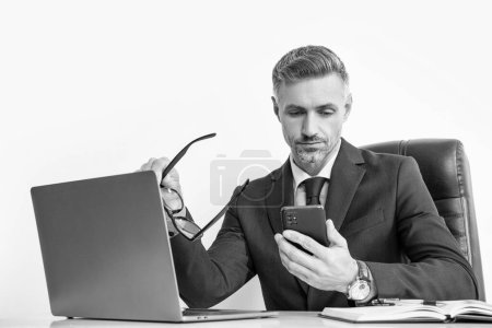 grizzled businessman with eyewear using phone in office with computer.