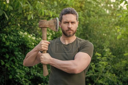 photo of bearded masculine guy hold sharp axe outdoor.