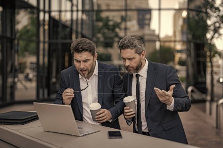 freelancer men have business online with laptop. photo of freelancer men have business online. two freelancer men have business online. freelancer men have business online outdoor.