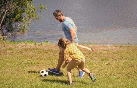 Father and son enjoy a friendly game of football. happy childhood of son playing with father. father and son summer activity. son has bonding time with father outdoor. embracing the great outdoors.