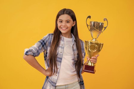 teen girl smile and hold her award champion cup isolated on yellow. teen girl receive award in studio. teen girl accept award on background. proud teen girl with champion cup award.