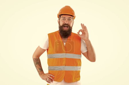 Téléchargez les photos : Heureux travailleur barbu en gilet orange. prise de vue en studio d'un travailleur portant un casque. travailleur isolé sur fond blanc. ouvrier en uniforme. - en image libre de droit