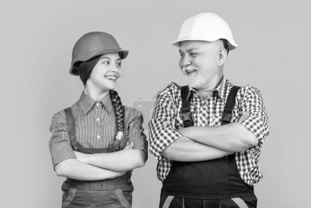 happy child kid and grandfather builder in hard hat on yellow background.