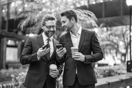 Photo for Photo of happy business colleagues with phone and coffee. business colleagues with phone in the street. business colleagues with phone outdoor. business colleagues with phone in suit. - Royalty Free Image