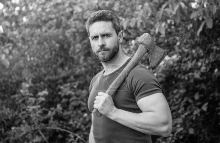 man holding axe outdoor. photo of man with axe. man with axe. man with axe wearing shirt.