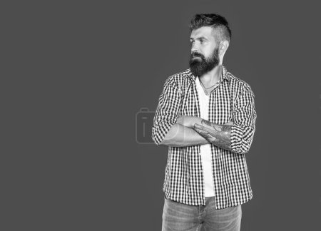 hombre barbudo adulto usar camisa a cuadros sobre fondo gris.